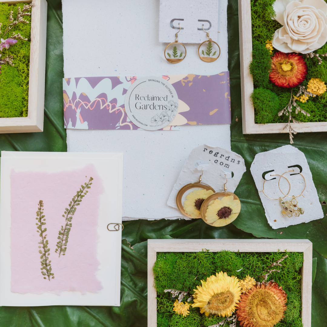 woman placing small moss art on wall in book store